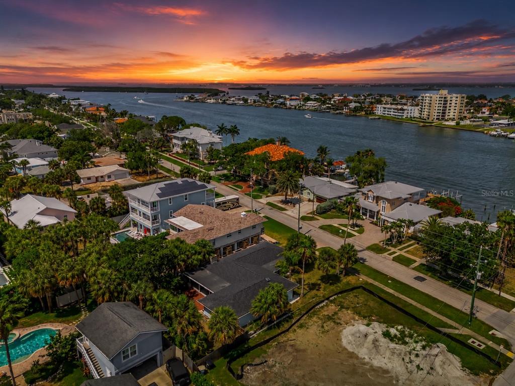 An aerial view of a coastal neighborhood at sunset with houses, palm trees, and water — 730 BAY ESPLANADE, CLEARWATER BEACH, FL