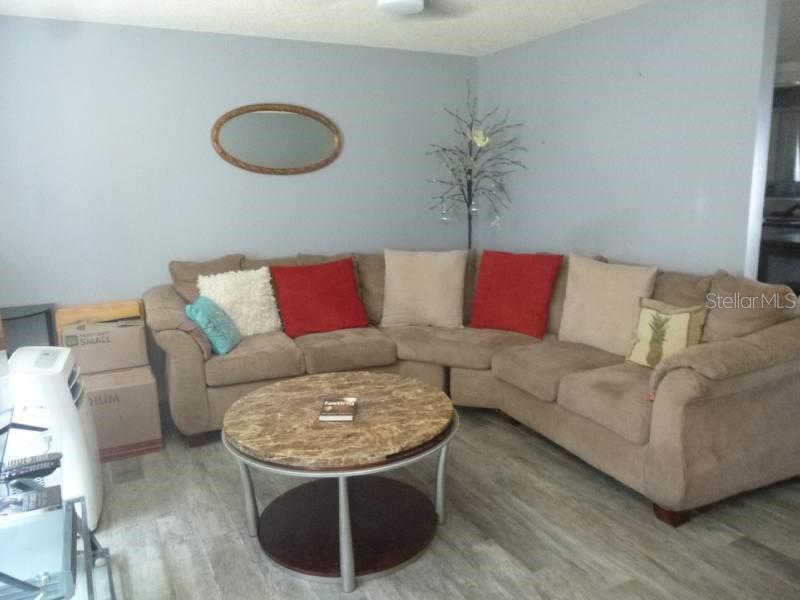 A living room features a large tan sectional sofa, a round coffee table, and a mirror — 528 CENTRAL AVENUE, FROSTPROOF, FL