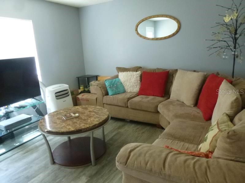 A living room features a brown sectional sofa, a round coffee table, and a television — 528 CENTRAL AVENUE, FROSTPROOF, FL