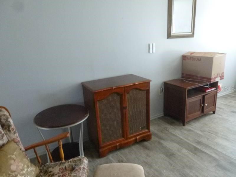 A room features light gray walls, wood-look flooring, a wooden cabinet, and a small side table — 528 CENTRAL AVENUE, FROSTPROOF, FL