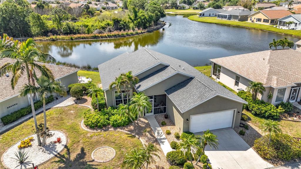 An aerial view shows a single-story house with a gray roof and garage near a lake — 24229 WESTGATE BOULEVARD, PUNTA GORDA, FL