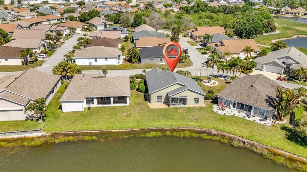 An aerial view shows a suburban house with a screened lanai overlooking a pond — 24229 WESTGATE BOULEVARD, PUNTA GORDA, FL