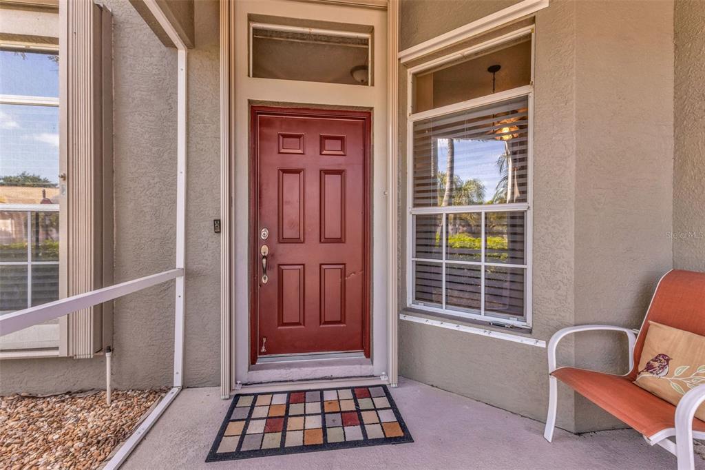 A red front door with a transom window sits on a covered porch with seating — 24229 WESTGATE BOULEVARD, PUNTA GORDA, FL