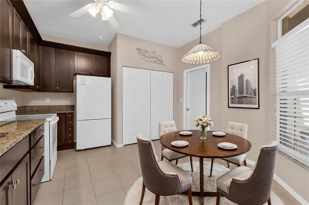 A kitchen and dining area with dark wood cabinets, granite countertops, and a round table — 24229 WESTGATE BOULEVARD, PUNTA GORDA, FL