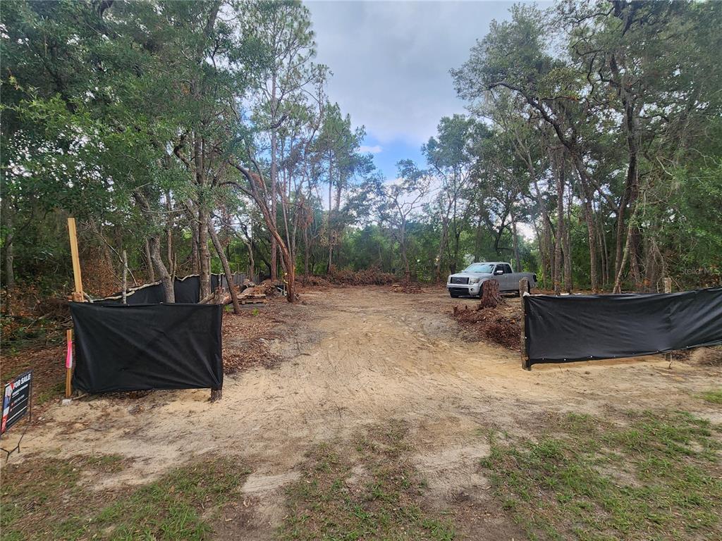 A cleared, sandy residential lot is enclosed by black silt fencing and surrounded by trees — 3919 E ORCHID STREET, HERNANDO, FL