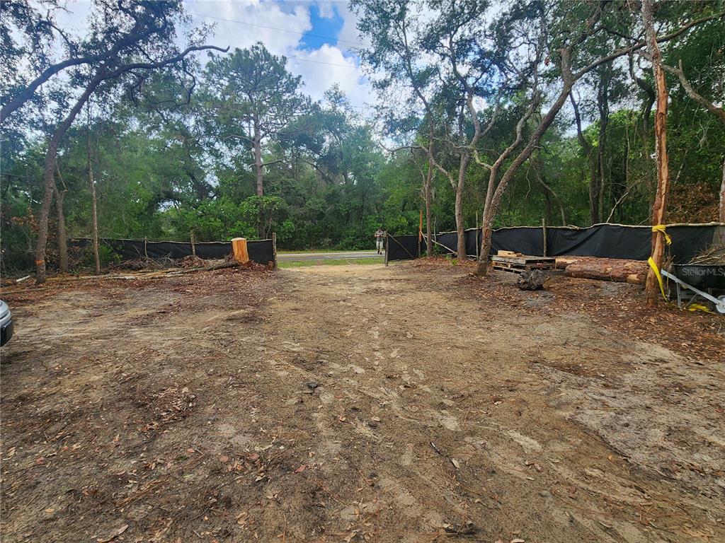 A cleared, sandy lot is enclosed by a black silt fence and surrounded by trees — 3919 E ORCHID STREET, HERNANDO, FL