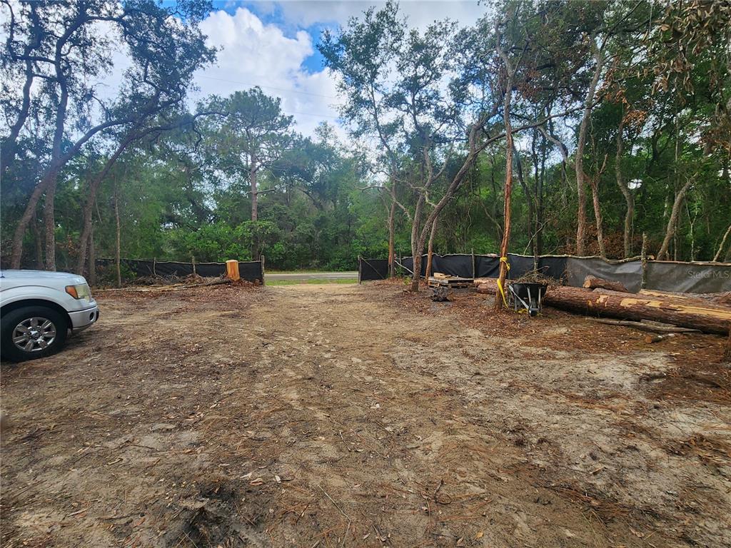 A dirt lot with a parked vehicle, a black construction fence, and surrounding trees — 3919 E ORCHID STREET, HERNANDO, FL