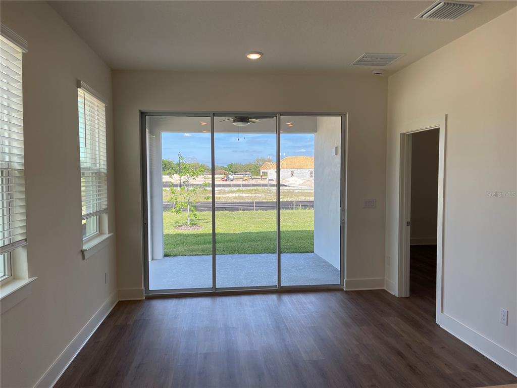 An interior room with wood-look flooring, sliding glass doors, and a view of a backyard — 3809 DAYBREAK RUN LOOP, SPRING HILL, FL