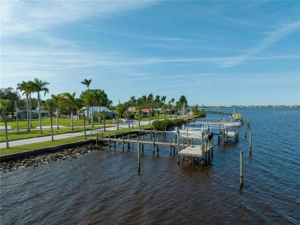 A view of a waterfront property featuring wooden docks, palm trees, and a paved road — 2520 RIVERSIDE DRIVE E, BRADENTON, FL