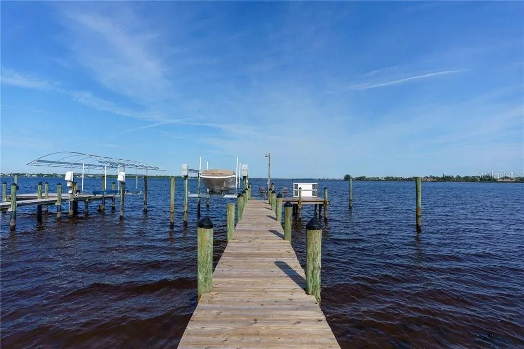 A wooden dock extends into a large body of water with boat lifts — 2520 RIVERSIDE DRIVE E, BRADENTON, FL