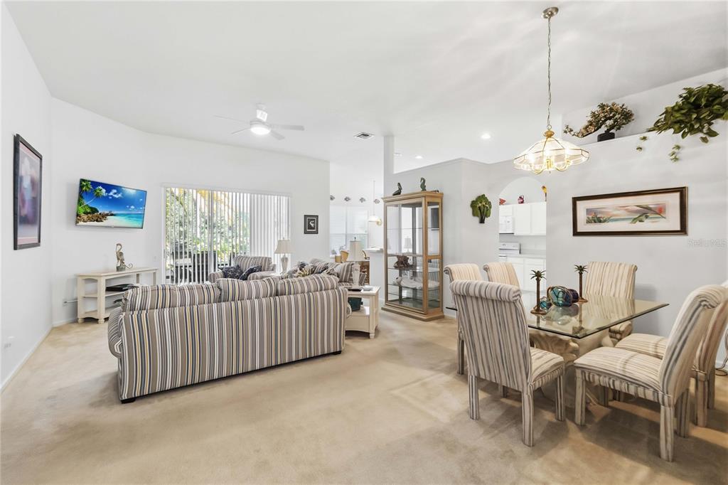 A living and dining room with striped furniture, a glass table, and a display cabinet — 3245 FALCON POINT DRIVE, KISSIMMEE, FL