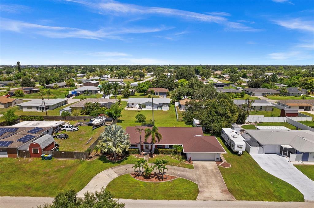 An aerial view of a single-story house with a brown roof and a concrete driveway — 22112 BRONXVILLE AVENUE, PORT CHARLOTTE, FL
