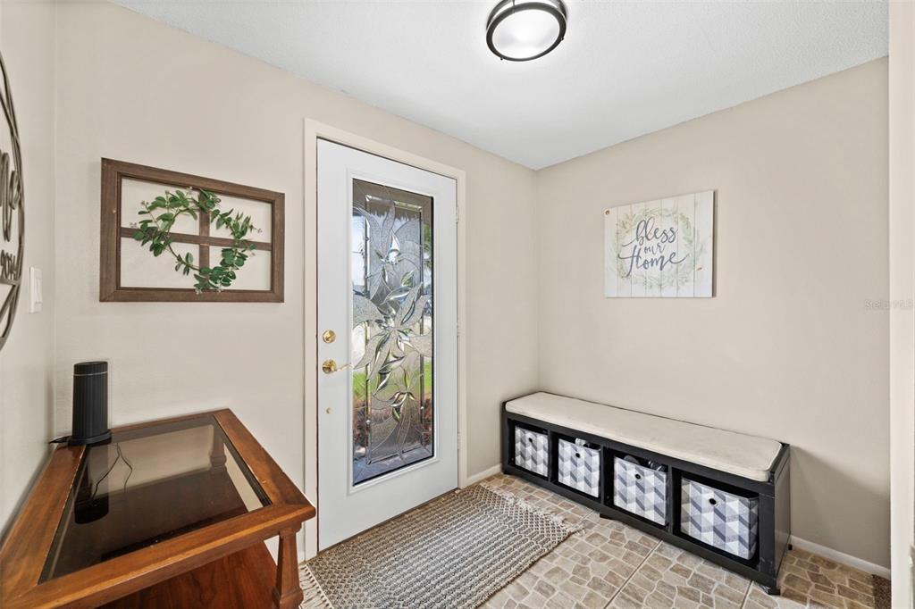 An entryway features a glass-paneled door, a storage bench with baskets, and a wooden table — 22112 BRONXVILLE AVENUE, PORT CHARLOTTE, FL