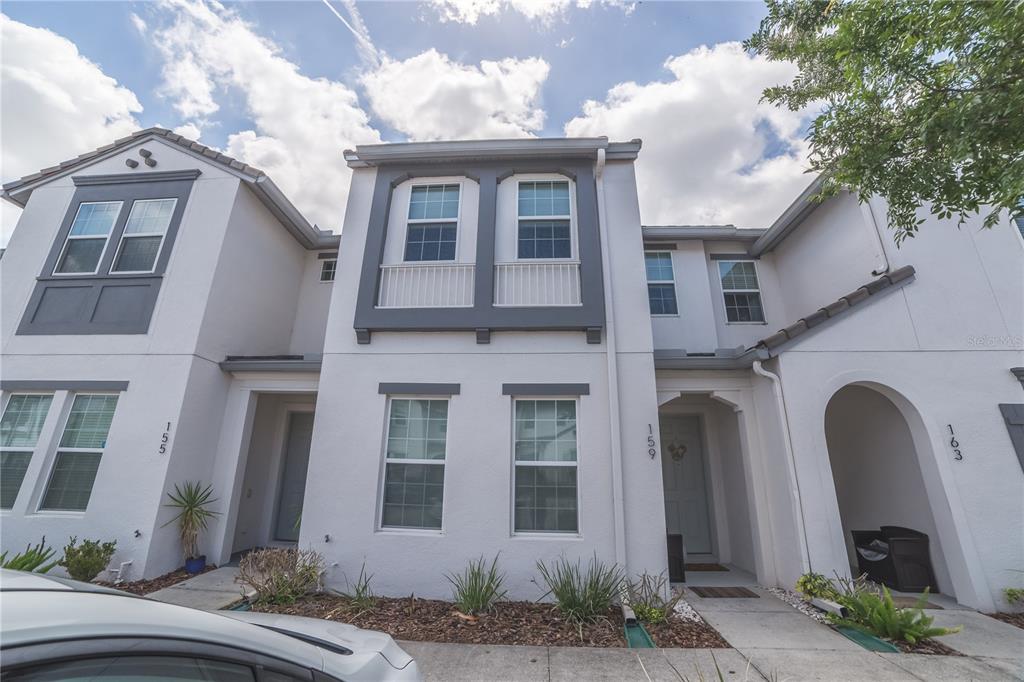 A row of three attached two-story townhomes with white stucco walls and grey trim — 159 CAPTIVA DRIVE, DAVENPORT, FL
