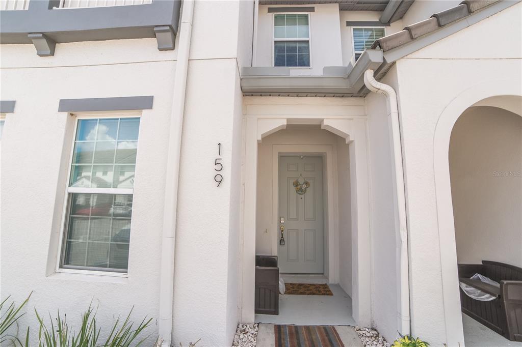 The exterior of a light-colored townhouse features a gray front door and house number 159 — 159 CAPTIVA DRIVE, DAVENPORT, FL