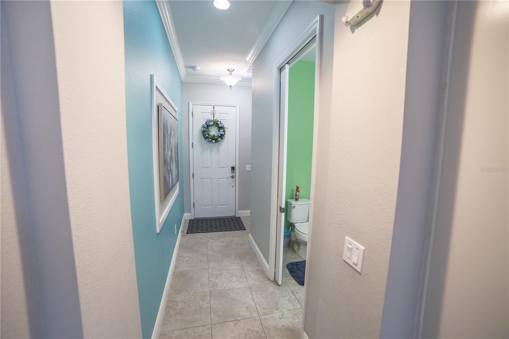A hallway with tiled floors leads to a front door and a small bathroom — 159 CAPTIVA DRIVE, DAVENPORT, FL