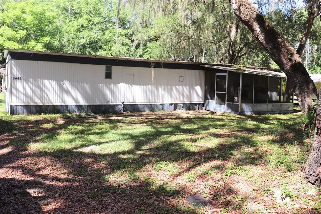 A single-wide mobile home with a screened-in porch sits on a wooded, grassy lot — 2466 CR 401A, LAKE PANASOFFKEE, FL