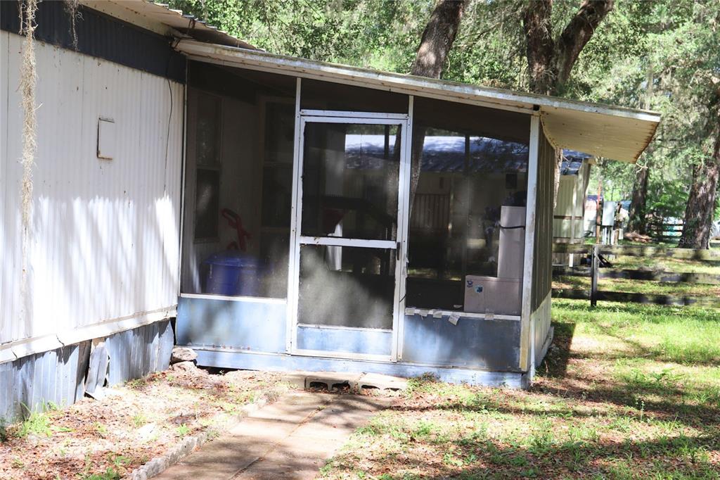 A mobile home features a screened-in porch with a metal roof and a concrete walkway — 2466 CR 401A, LAKE PANASOFFKEE, FL