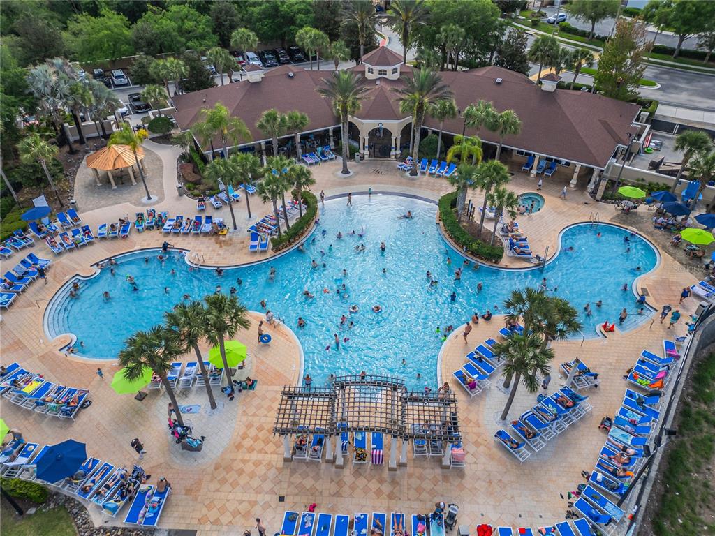 An aerial view shows a large resort-style swimming pool surrounded by lounge chairs and palm trees — 2817 ALMATON LOOP UNIT 402, KISSIMMEE, FL