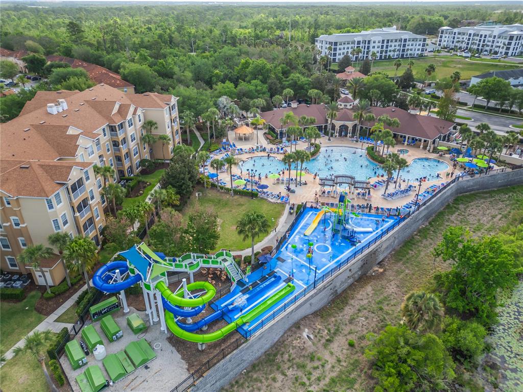 An aerial view shows a large apartment complex with a swimming pool and water slides — 2817 ALMATON LOOP UNIT 402, KISSIMMEE, FL