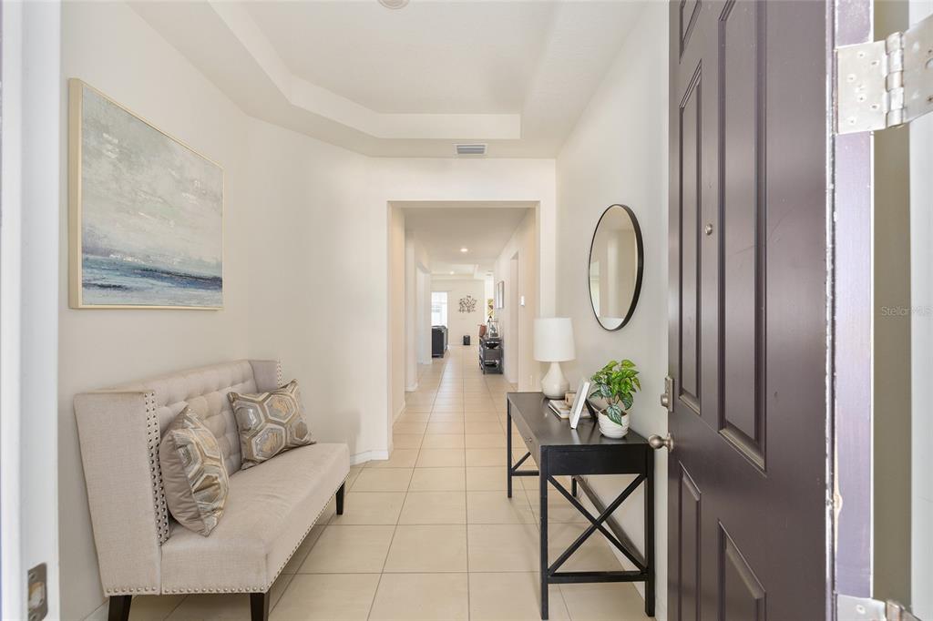 A foyer features a tufted bench, a console table with a mirror, and tiled flooring — 8285 SW 58TH AVENUE, OCALA, FL