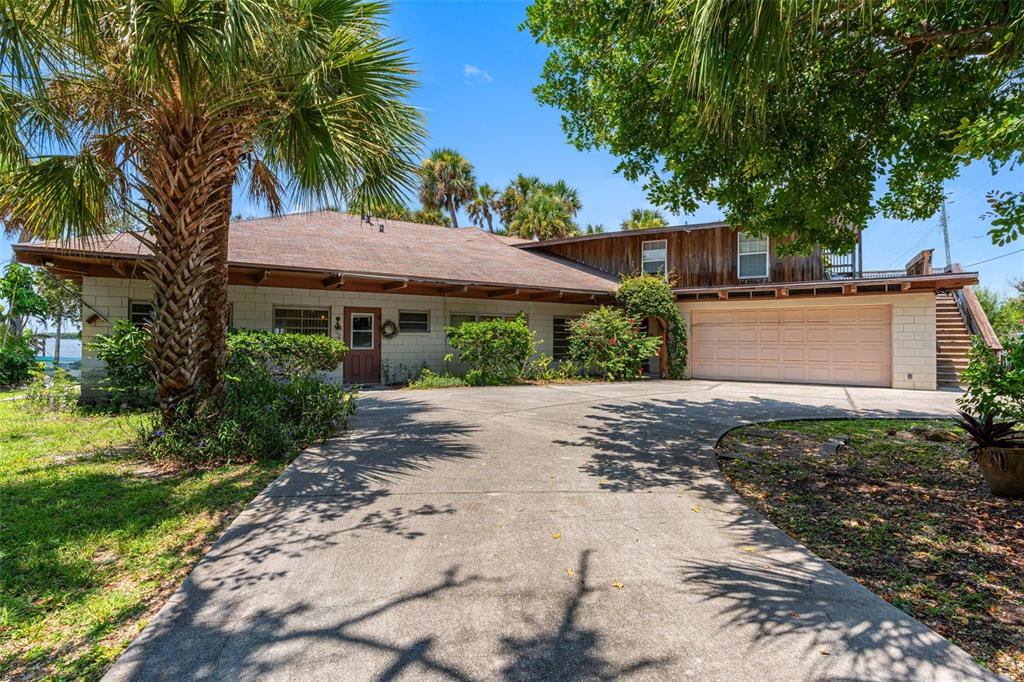 A single-story house with a concrete block exterior, a two-car garage, and a palm tree — 1230 S ORLANDO AVENUE, COCOA BEACH, FL