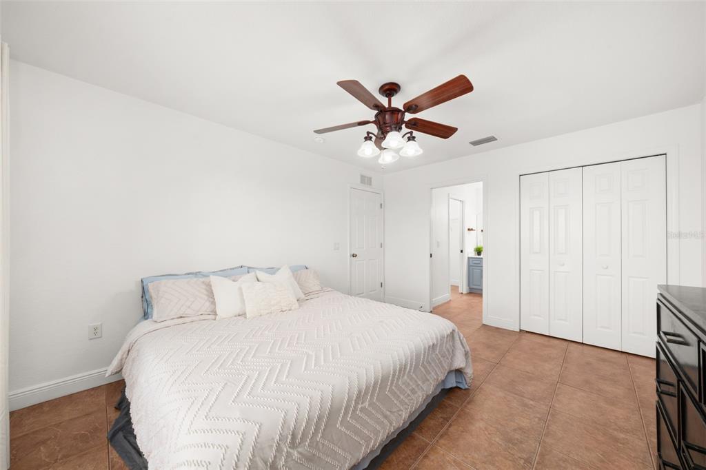 A bedroom features a bed with a textured quilt, tile flooring, and a ceiling fan — 615 GRAHAM DAIRY RD, VENUS, FL