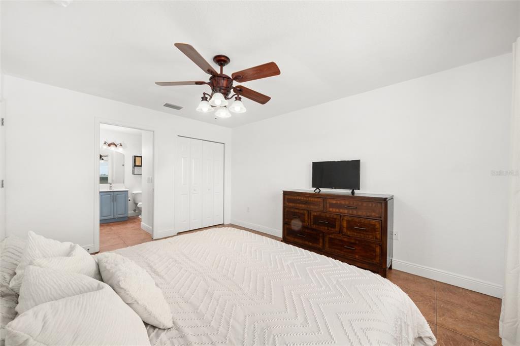 A bedroom features a bed, a wooden dresser with a television, and an attached bathroom — 615 GRAHAM DAIRY RD, VENUS, FL