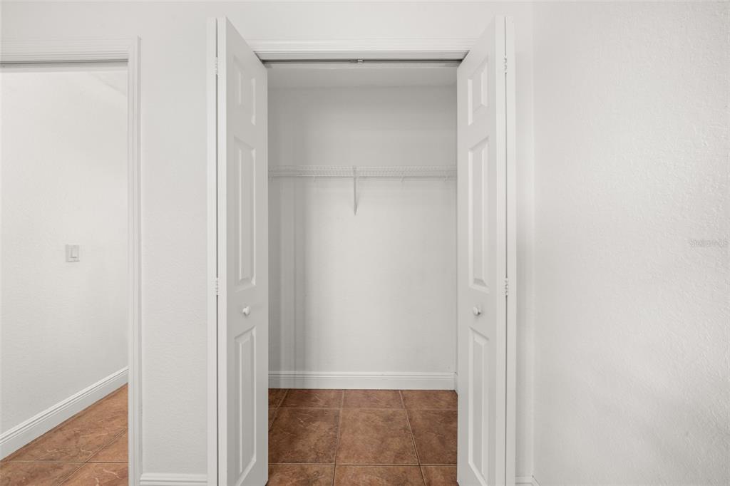 An open white closet with a wire shelf stands against a wall with tiled flooring — 615 GRAHAM DAIRY RD, VENUS, FL