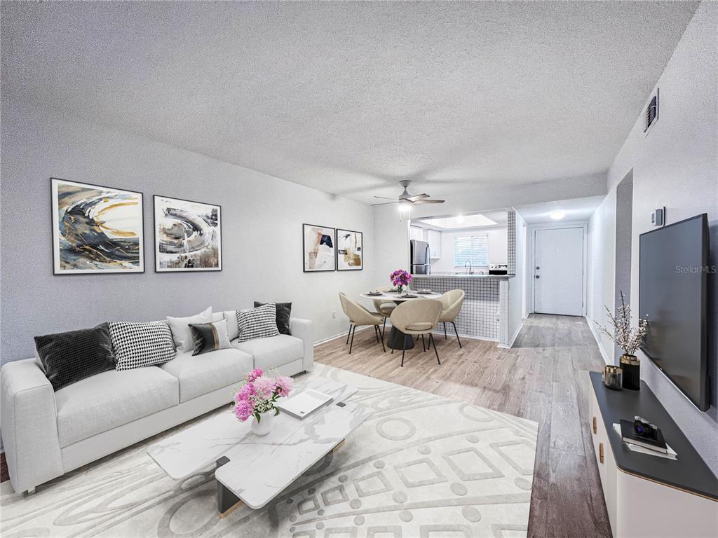 A living room and dining area with light wood floors, a white sofa, and kitchen — 4204 HERON WAY UNIT B304, BRADENTON, FL