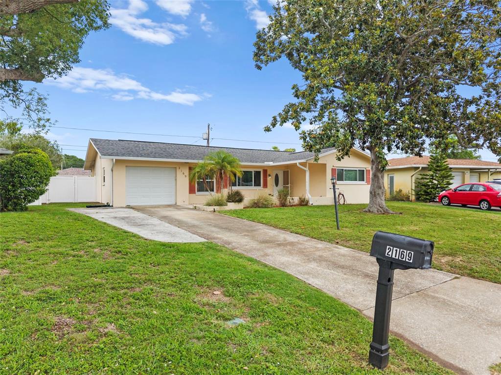 A single-story house with a white garage, a concrete driveway, and a mailbox in front — 2169 PINE RIDGE DRIVE, CLEARWATER, FL