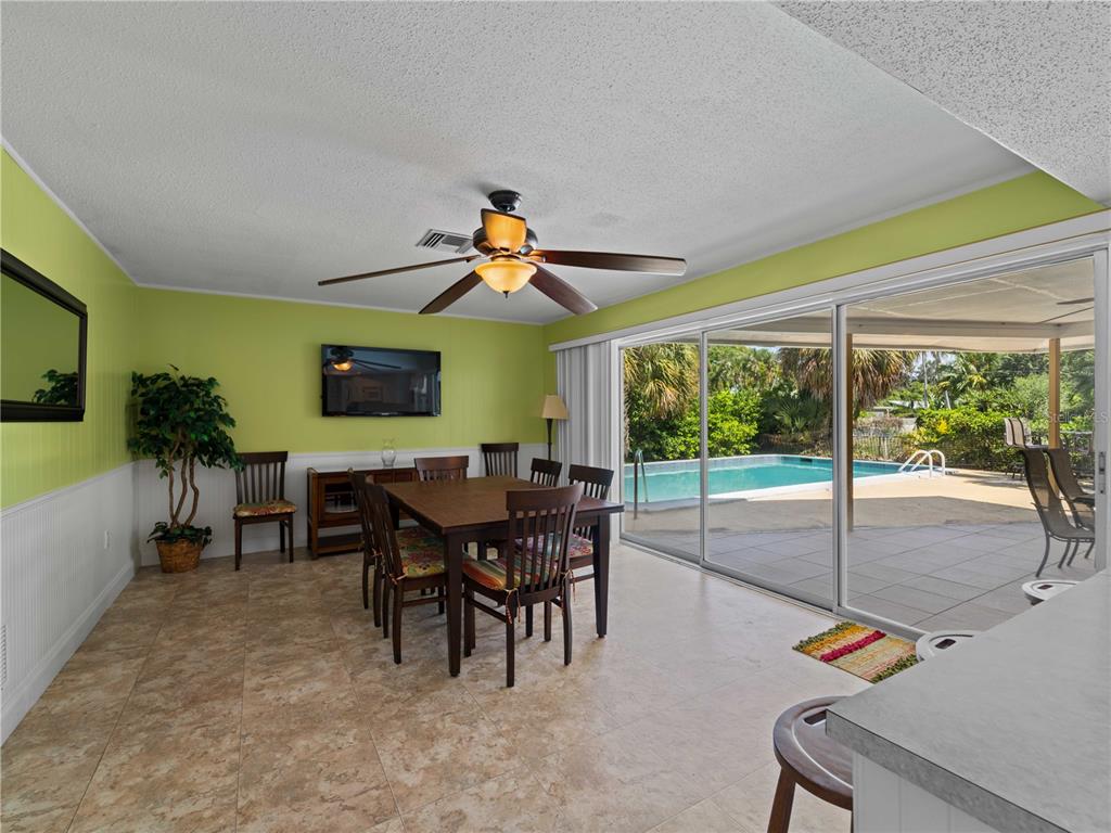 A dining room with lime green walls, tile flooring, and sliding doors opening to a pool — 424 BAYCREST DRIVE, VENICE, FL