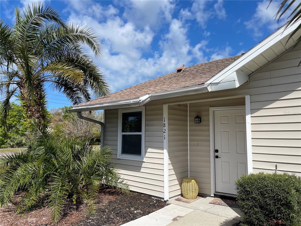 The exterior of a beige, single-story house features a palm tree and a front entrance — 1821 ORANGE BOULEVARD WAY, PALM HARBOR, FL