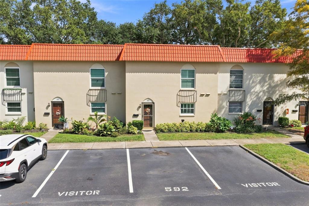 An exterior view of a two-story townhouse complex with visitor parking spaces in front — 2700 BAYSHORE BOULEVARD UNIT 592, DUNEDIN, FL