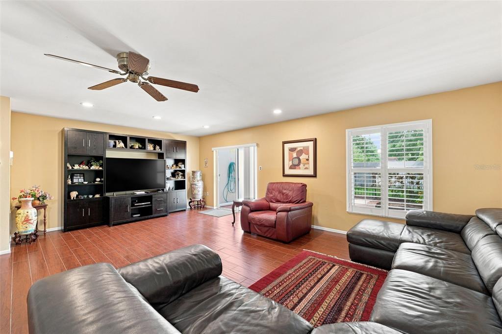 A living room with tile floors, a large entertainment center, and a leather sectional sofa — 2700 BAYSHORE BOULEVARD UNIT 592, DUNEDIN, FL