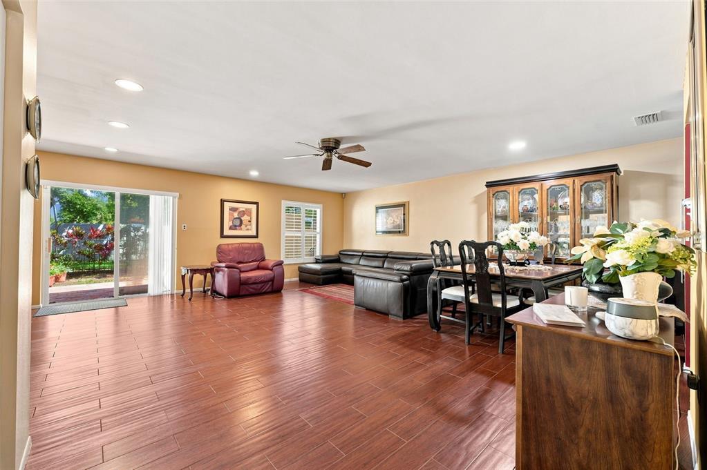 A spacious living and dining area with wood-look flooring, a leather sectional, and sliding doors — 2700 BAYSHORE BOULEVARD UNIT 592, DUNEDIN, FL
