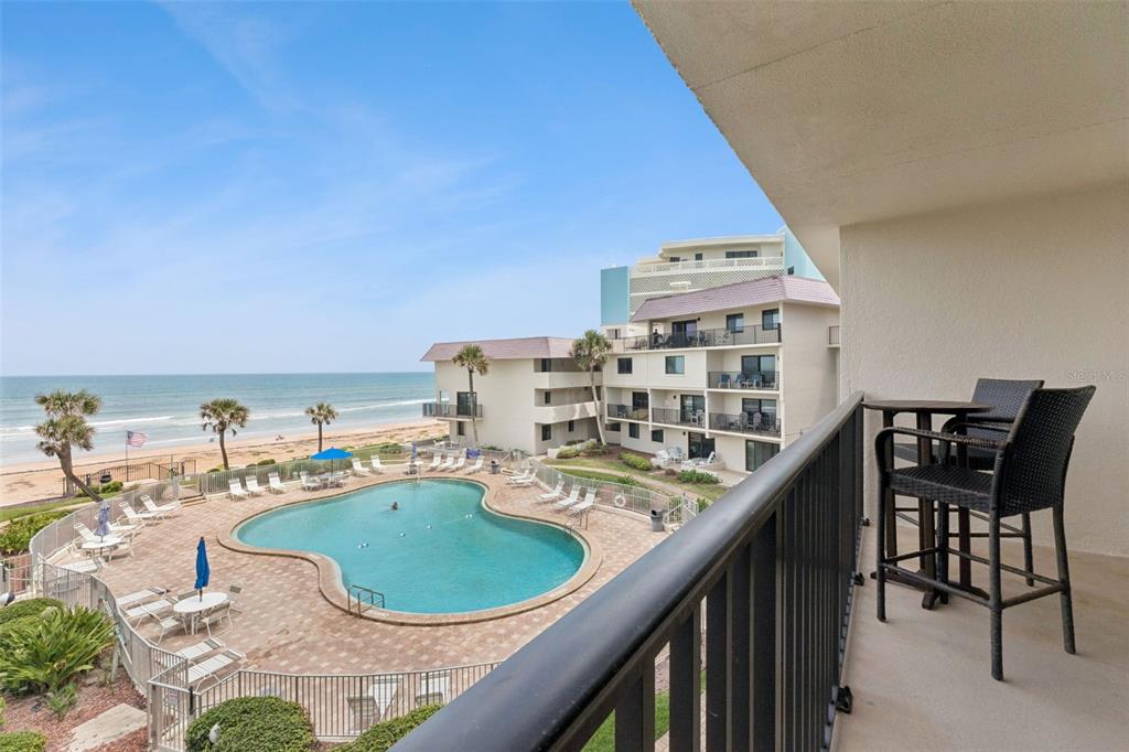 A balcony view overlooks a swimming pool, a multi-story building, and the ocean beach — 935 OCEAN SHORE BOULEVARD UNIT 3020, ORMOND BEACH, FL