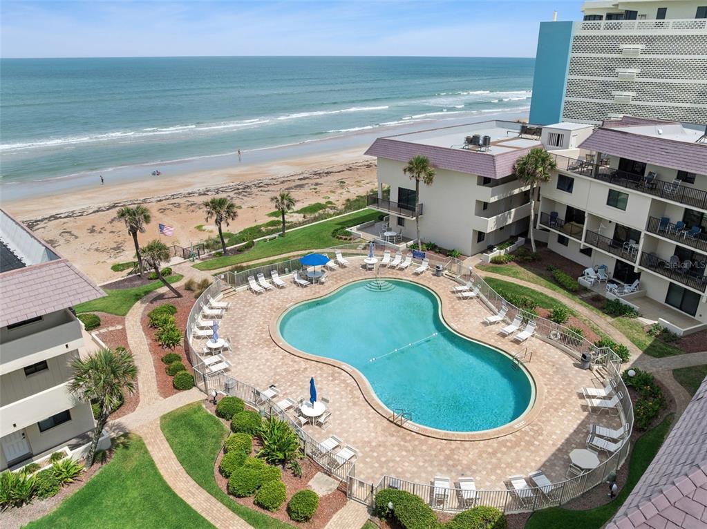 An elevated view of a swimming pool surrounded by a patio and beachside resort buildings — 935 OCEAN SHORE BOULEVARD UNIT 3020, ORMOND BEACH, FL