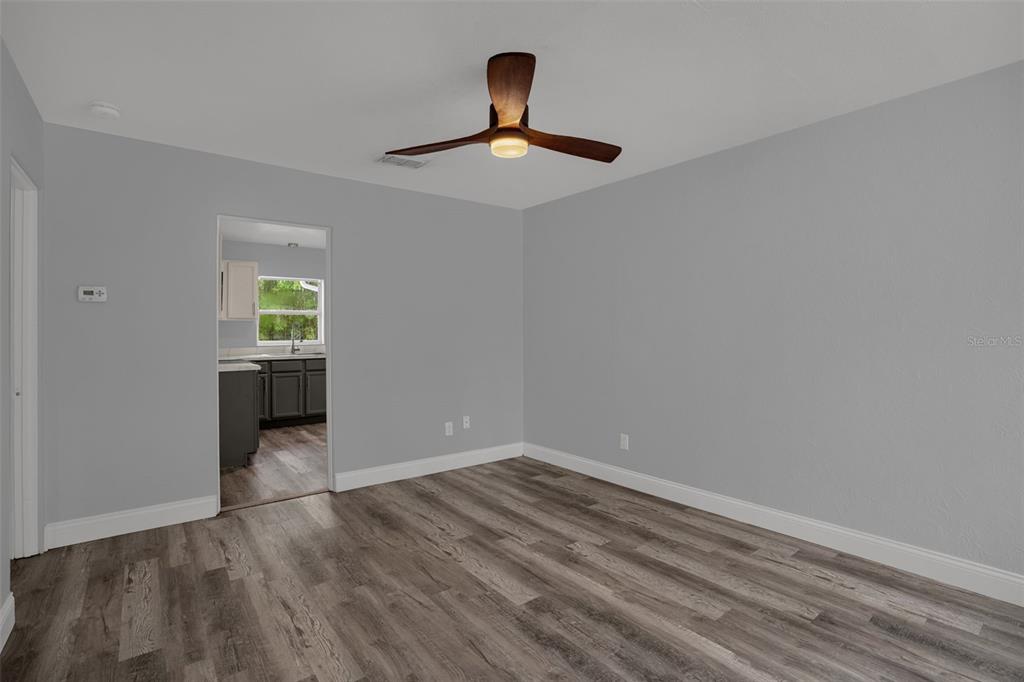 A sunroom with gray wood-look flooring and large windows overlooking a fenced backyard — 981 ARAGON AVENUE, WINTER PARK, FL