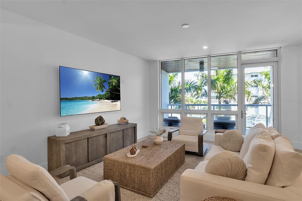 A covered balcony with wood-paneled ceilings, tiled floors, and outdoor seating overlooking a sandy beach — 1035 SEASIDE DRIVE UNIT 308, SARASOTA, FL