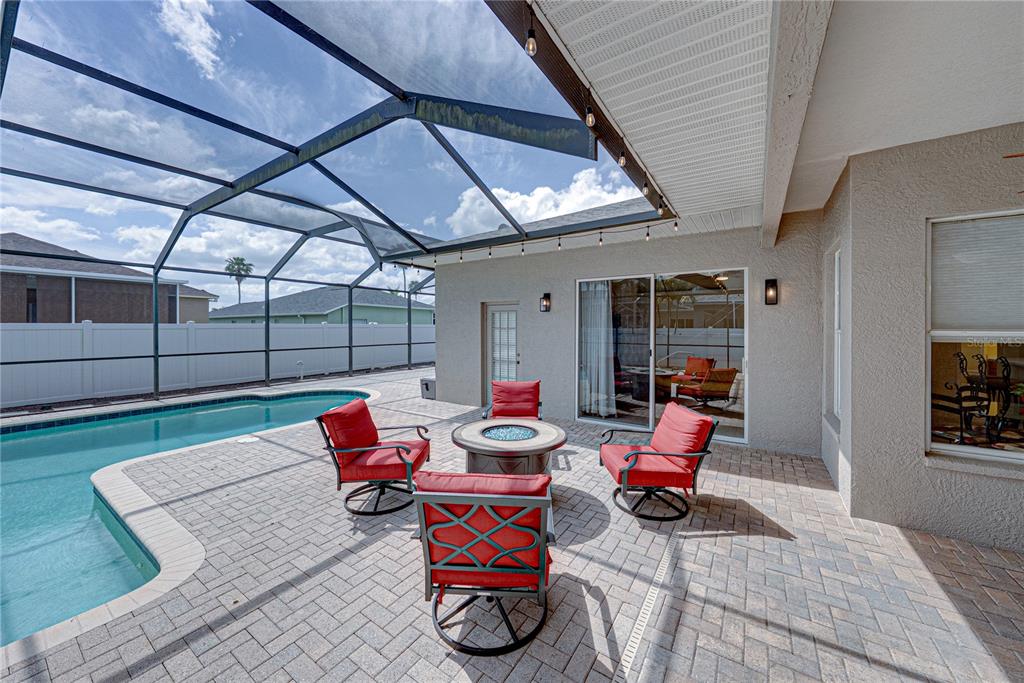 A screened-in patio features a pool, a fire pit, and four red chairs — 1542 SWAMP ROSE LANE, TRINITY, FL