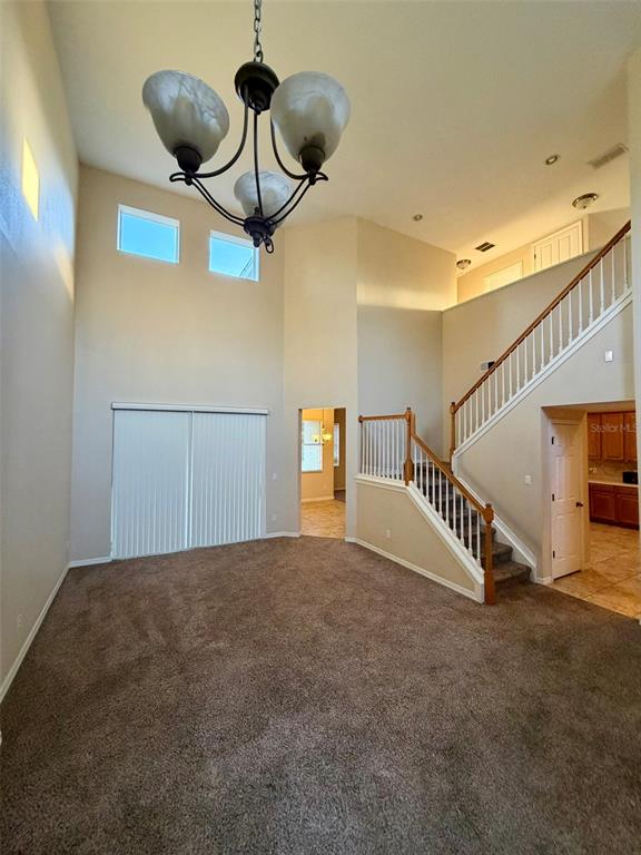 A living room with high ceilings, a chandelier, carpeted flooring, and a staircase — 6224 ZANE DRIVE, MOUNT DORA, FL