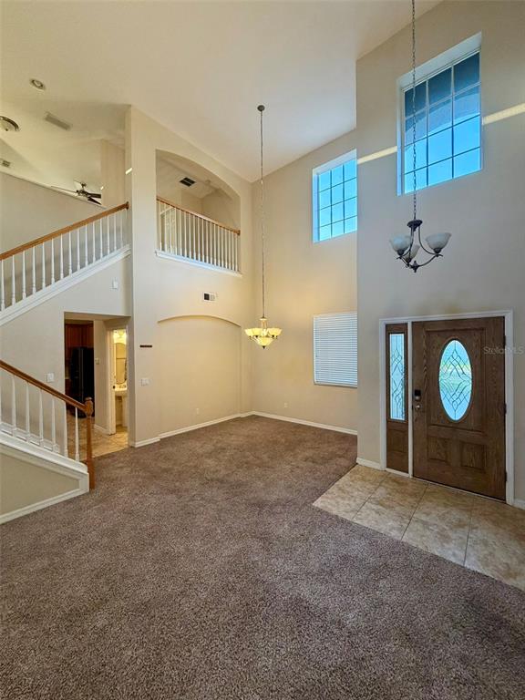 A two-story foyer features a carpeted floor, a wooden staircase, and two hanging light fixtures — 6224 ZANE DRIVE, MOUNT DORA, FL