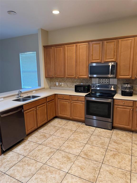 A kitchen features wood cabinets, stainless steel appliances, tile flooring, and a double sink — 6224 ZANE DRIVE, MOUNT DORA, FL