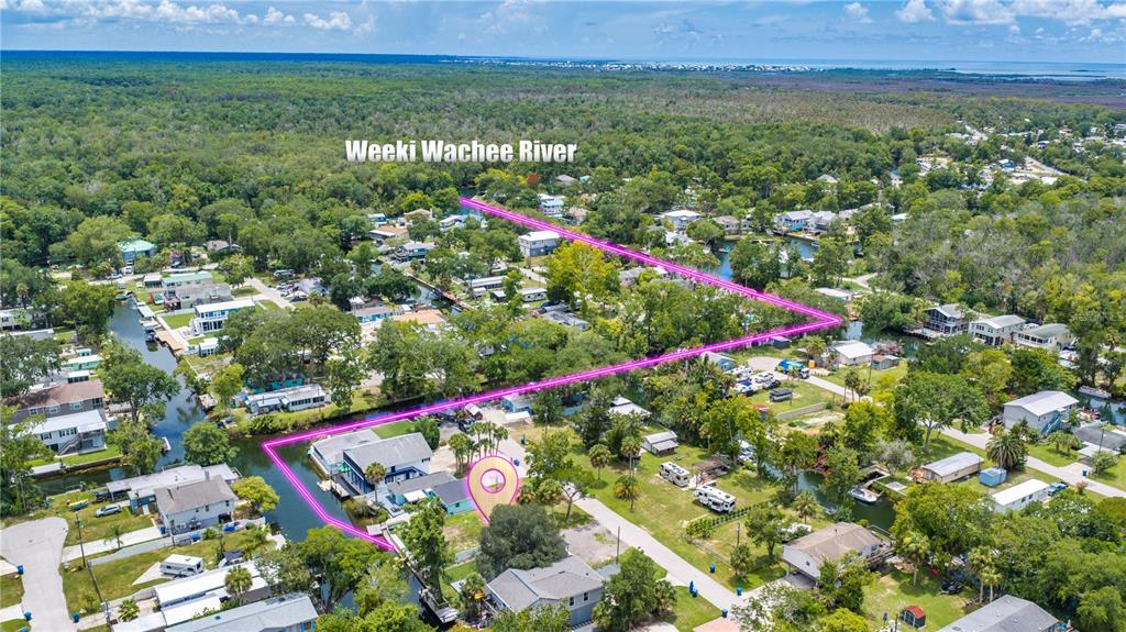 An aerial view shows a vacant rectangular waterfront lot outlined in pink with a dock — 7250 COVENTRY COURT, WEEKI WACHEE, FL