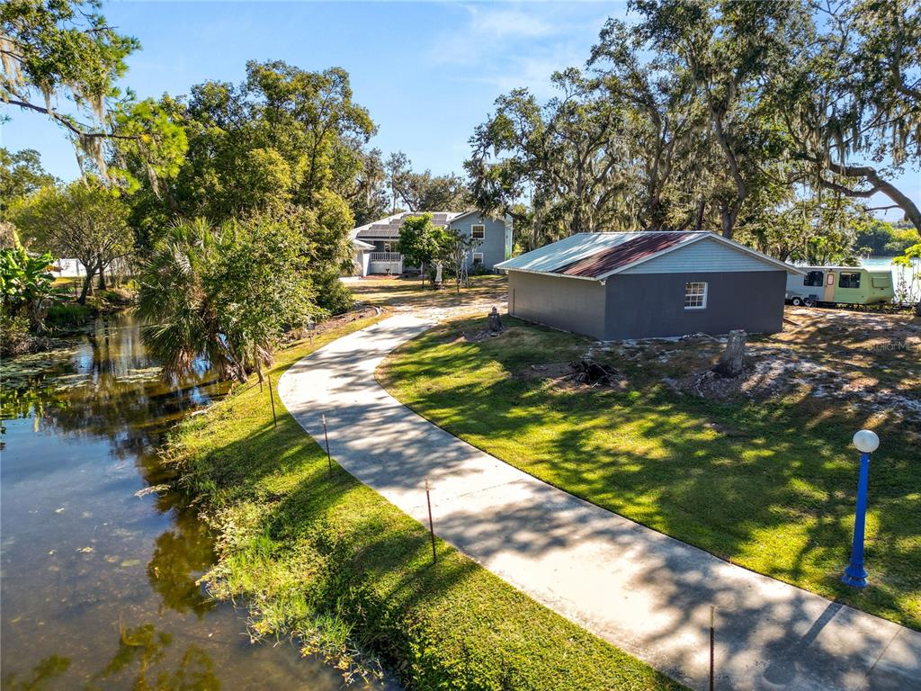 An aerial view shows a house and a small shed situated beside a lake — 109 NE 4TH AVENUE, MULBERRY, FL