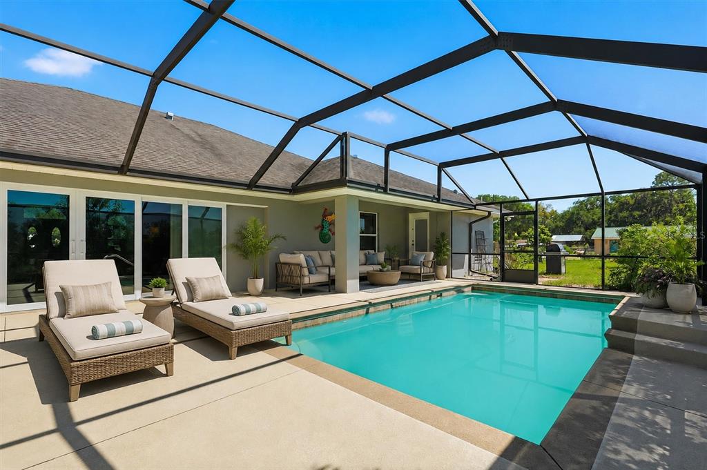 A screened-in patio features a rectangular swimming pool, lounge chairs, and outdoor seating furniture — 12764 COUNTY ROAD 223, OXFORD, FL