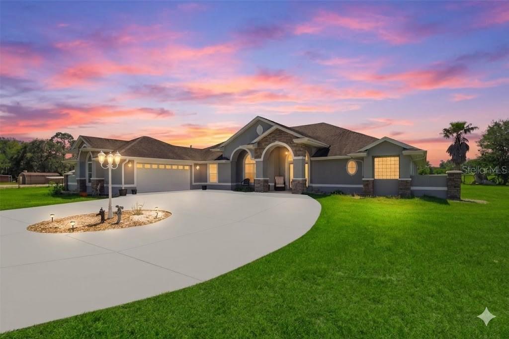 A single-story house with a gray exterior, stone accents, and a large circular concrete driveway — 12764 COUNTY ROAD 223, OXFORD, FL