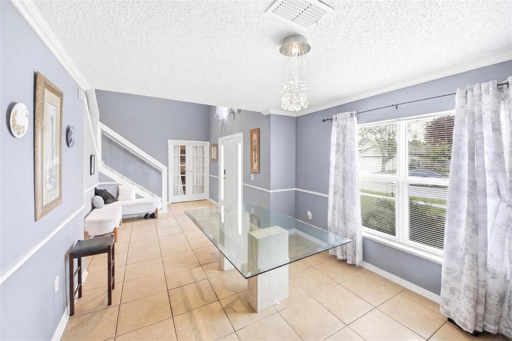 A dining room features a glass-topped table, tile flooring, light blue walls, and a chandelier — 1912 MAURY ROAD, ST CLOUD, FL