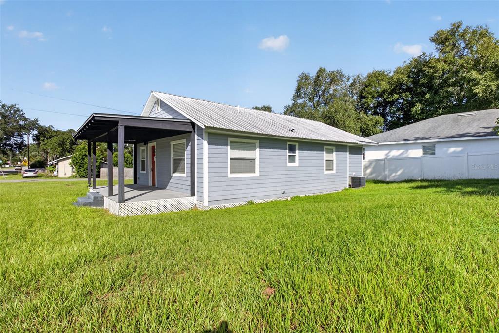 A light blue house with a metal roof and a covered front porch sits on grass — 4104 ORANGE AVENUE SE, HIGHLAND CITY, FL